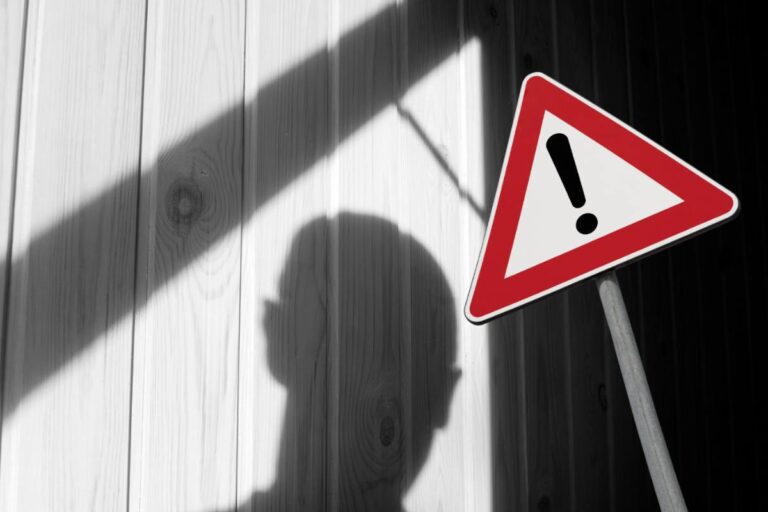 uomo nell'ombra e segnale di pericolo