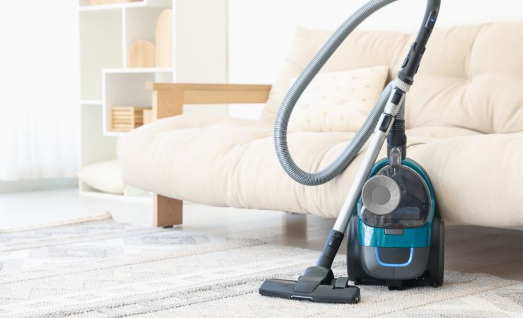 aspirapolvere poggiata vicino al divano in soggiorno 