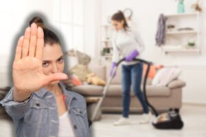 donna che passa aspirapolvere in casa e un'altra che fa stop con le mani