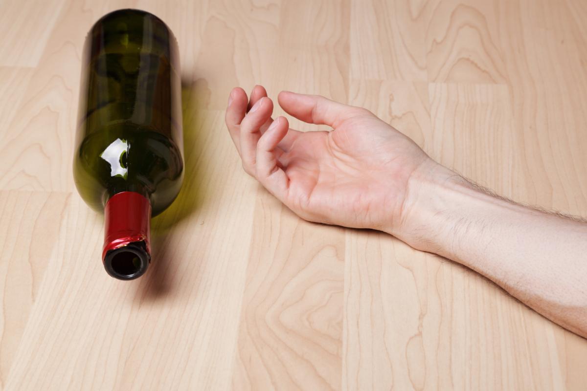 bottiglia di vino e braccio sul pavimento