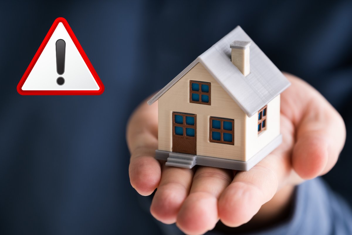 casa in miniatura e segnale di attenzione