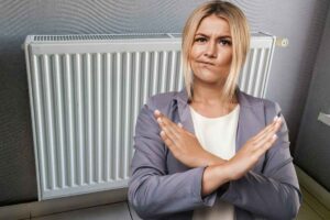 Donna fa X con le braccia, termosifone dietro di lei