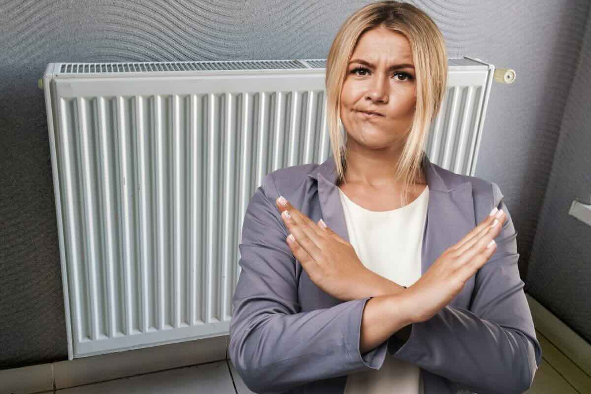Donna fa X con le braccia, termosifone dietro di lei